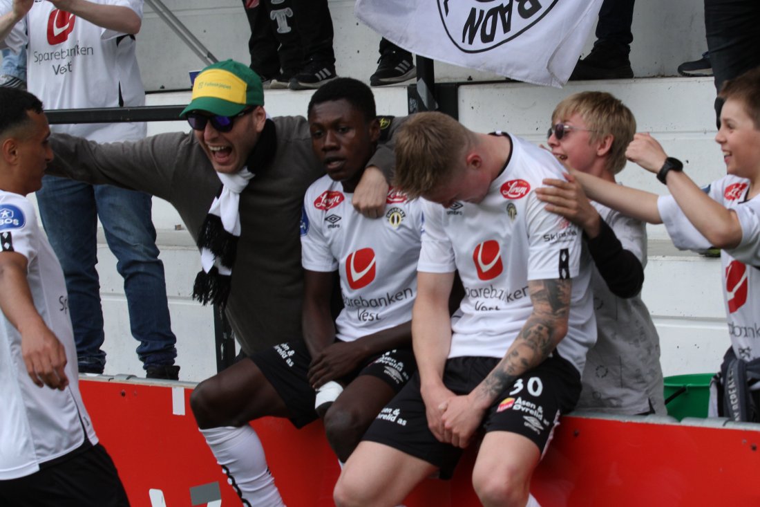 Edmund Baidoo på reklameskiltet framfor supportarane